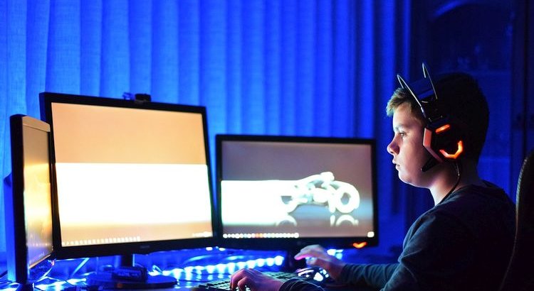 gamer sitting at 3 monitors